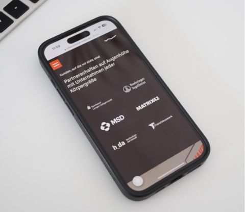 Smartphone mit dem Abschnitt der Kundenlogos auf der Website von Silberschmidt Media