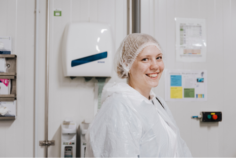 Eine freundlich l&auml;chelnde Mitarbeiterin von Silberschmidt Media tr&auml;gt Hygiene-Schutzkleidung.