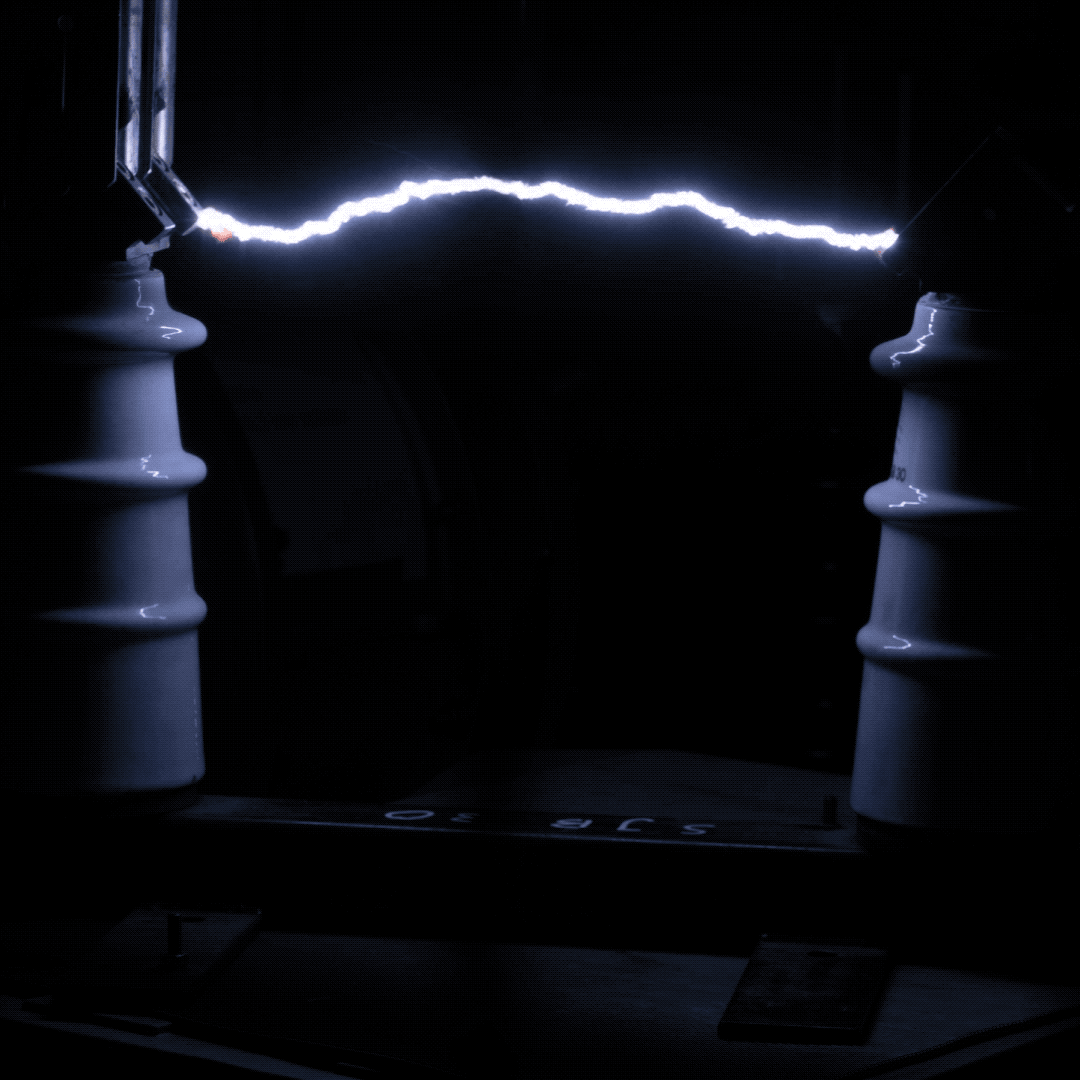 Elektrischer Lichtbogen zwischen zwei Isolatoren in einer Hochspannungsumgebung.